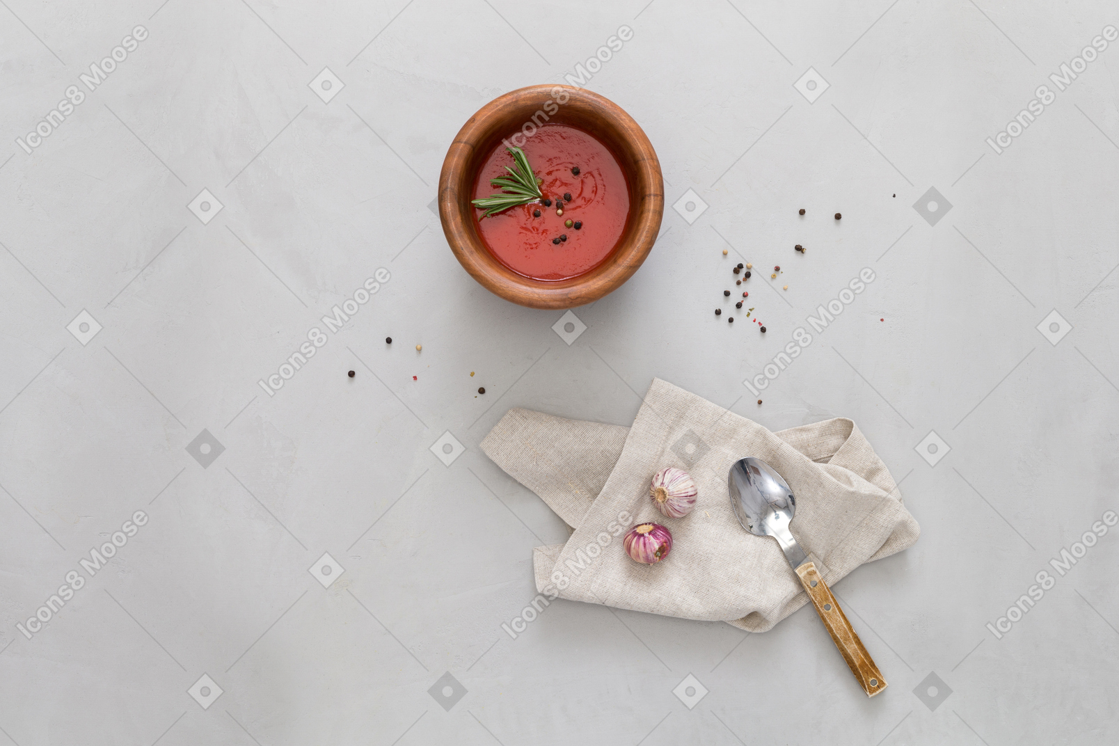 Eine schüssel gazpacho, etwas knoblauch und einen löffel