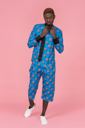 Black man in blue pajamas standing on the pink background