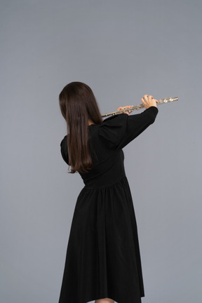 Black view of a young lady in black dress playing the flute