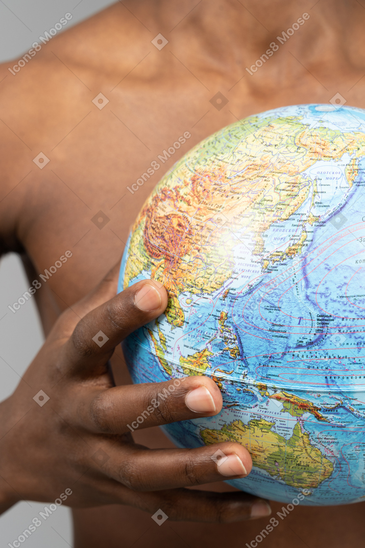 A shirtless young man holding the earth globe