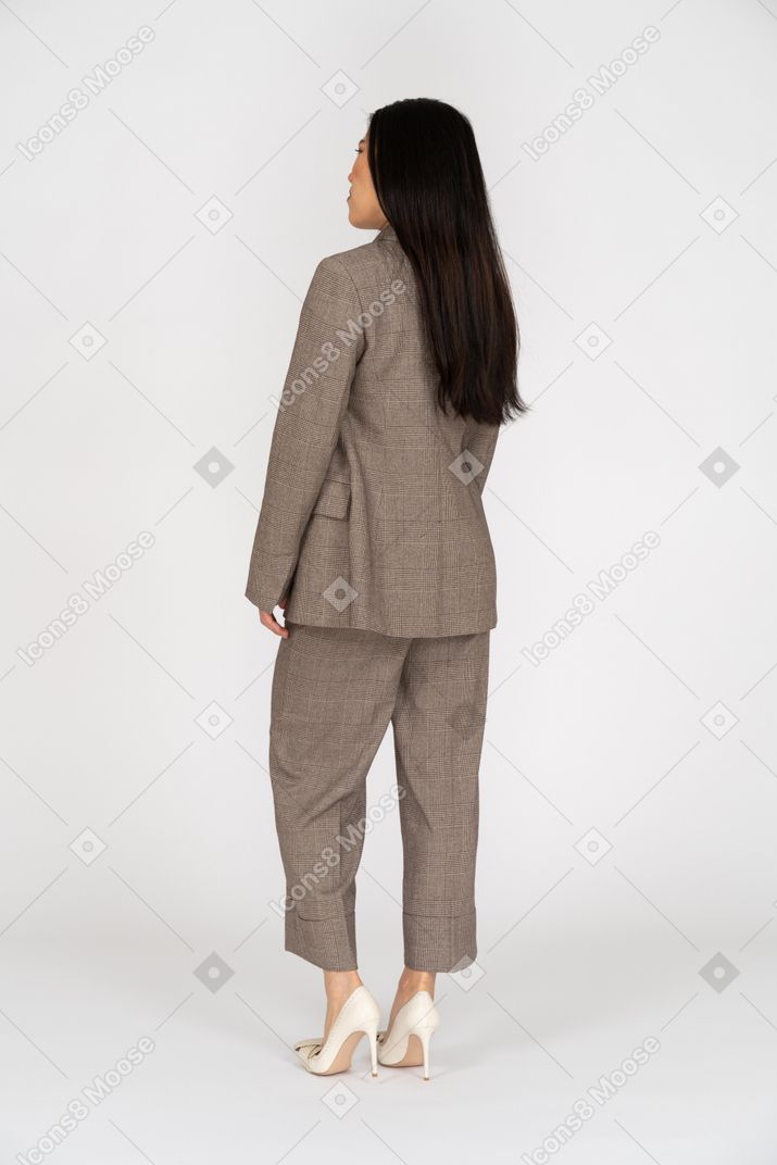 Dreiviertel-rückansicht einer unzufriedenen jungen dame im braunen business-anzug
