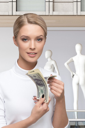 A woman holding money in front of mannequins