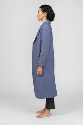Вид сбоку на женщину в синем пальто с нахмуренными бровями