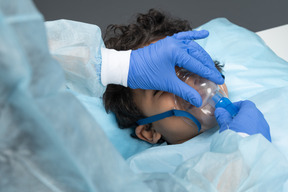 Médico colocando máscara de oxigênio no menino