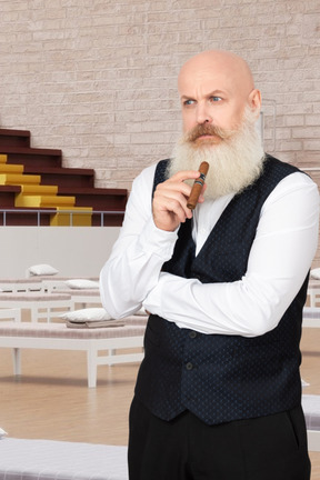 Pensive old man with a sigare standing in front of hospital beds