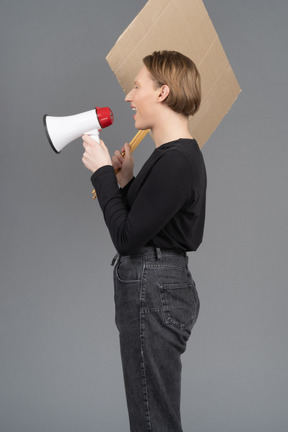 Side view of person with megaphone and sign in hand shouting