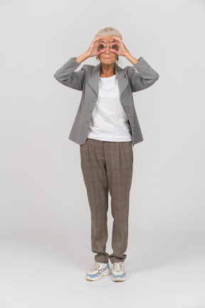 一位身着西装的老妇人通过想象中的双筒望远镜看着相机的前视图