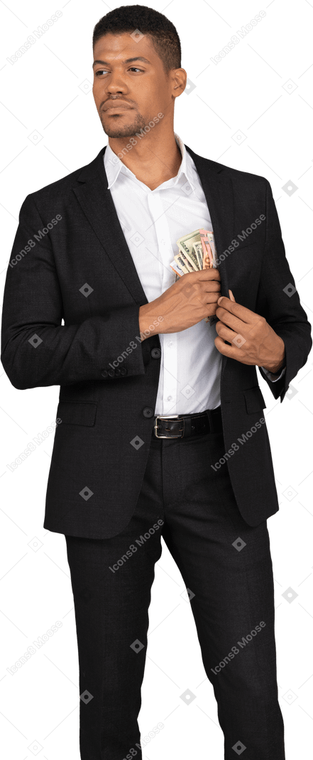 Front view of a young man in black suit putting banknotes into the pocket