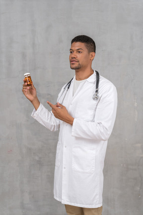 Young doctor pointing at a pill bottle