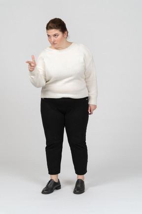 Vista frontal de uma mulher gorda em roupas casuais apontando com um dedo