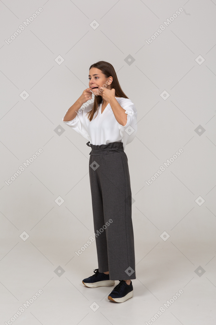 Vista de tres cuartos de una joven haciendo muecas en ropa de oficina