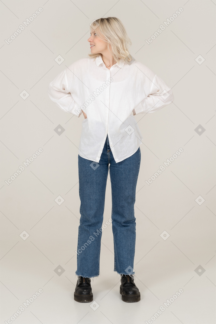 Vista frontale di una donna bionda in abiti casual, mettendo le mani sui fianchi e guardando a sinistra