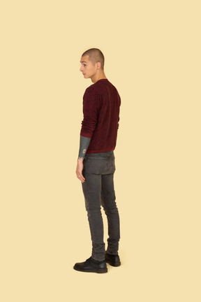 Vista traseira de três quartos de um jovem com um suéter vermelho