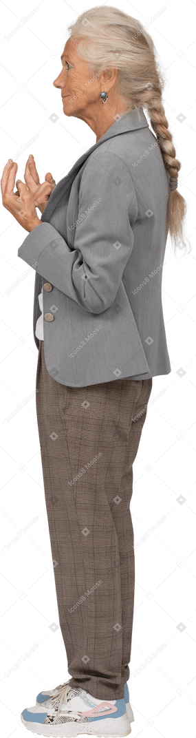 Side view of an old lady in suit crossing fingers
