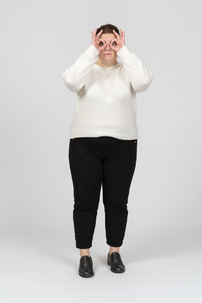 Mulher plus size com roupas casuais olhando através de binóculos imaginários