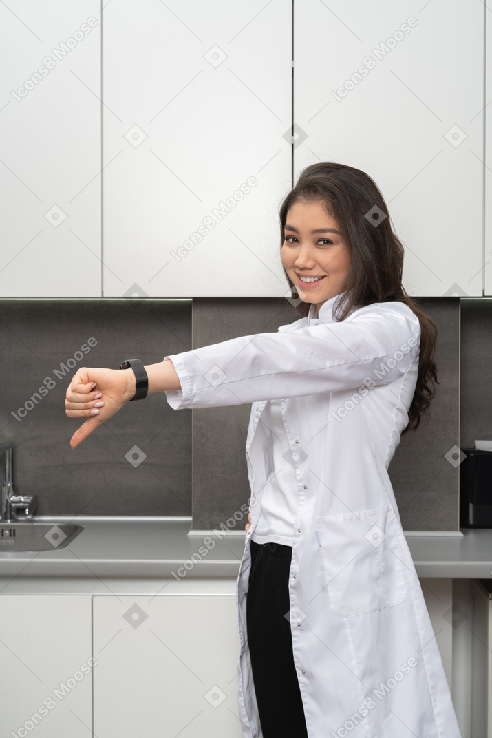 A smiling female doctor showing a dislike gesture