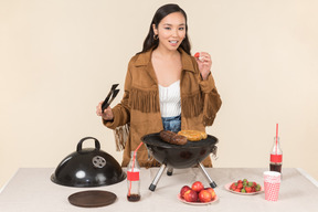 Joven asiática haciendo barbacoa y comiendo fresa