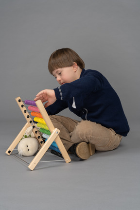 Side view of a little boy using an abacus