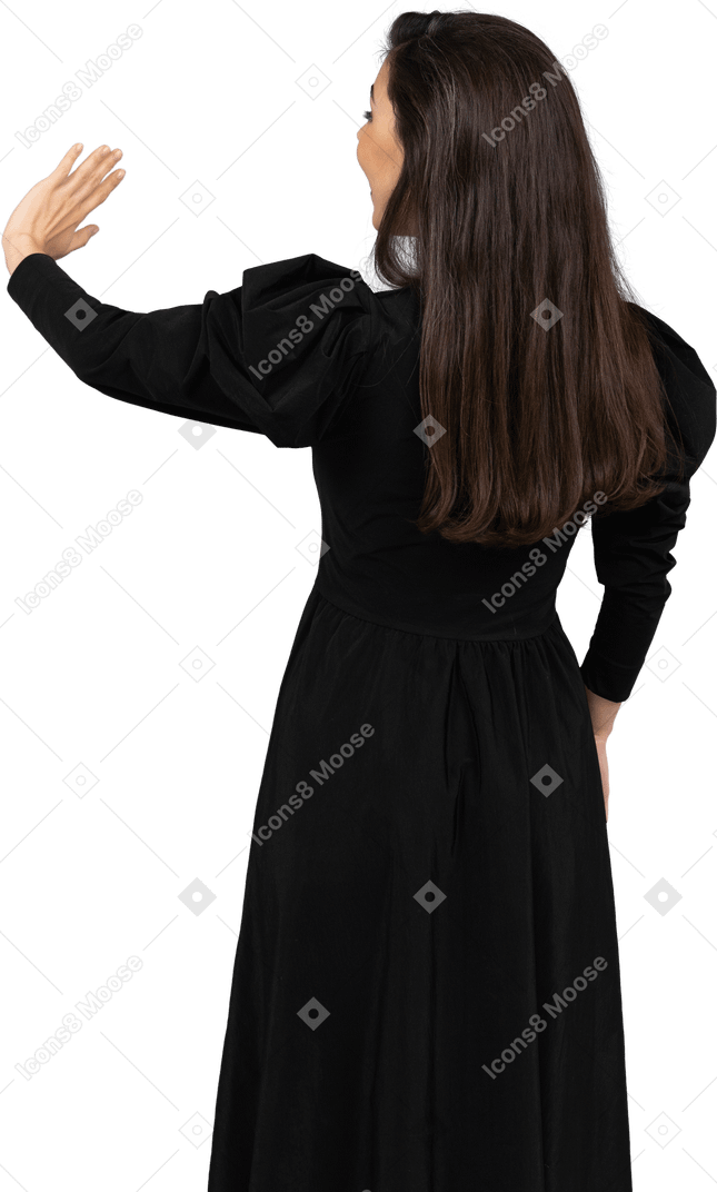 Back view of a young lady in a black dress raising her hand