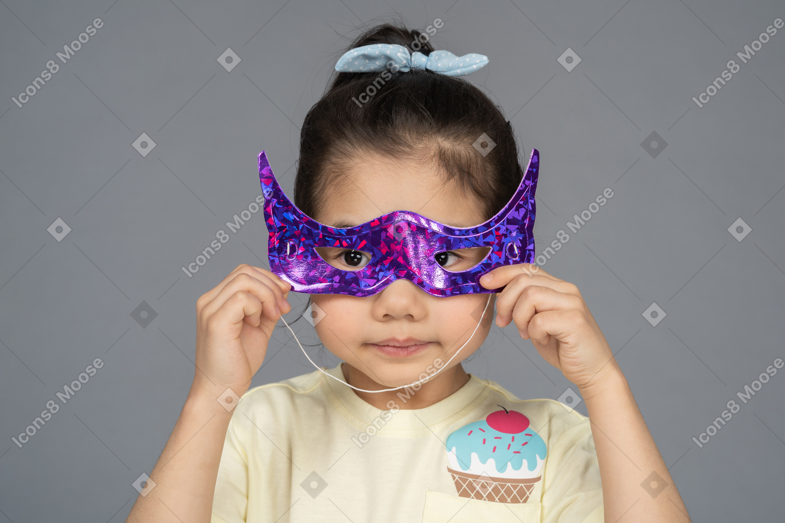 Close-up of a little girl trying on a superhero mask