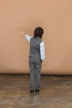 Rear view of a boy in grey suit showing thumb up