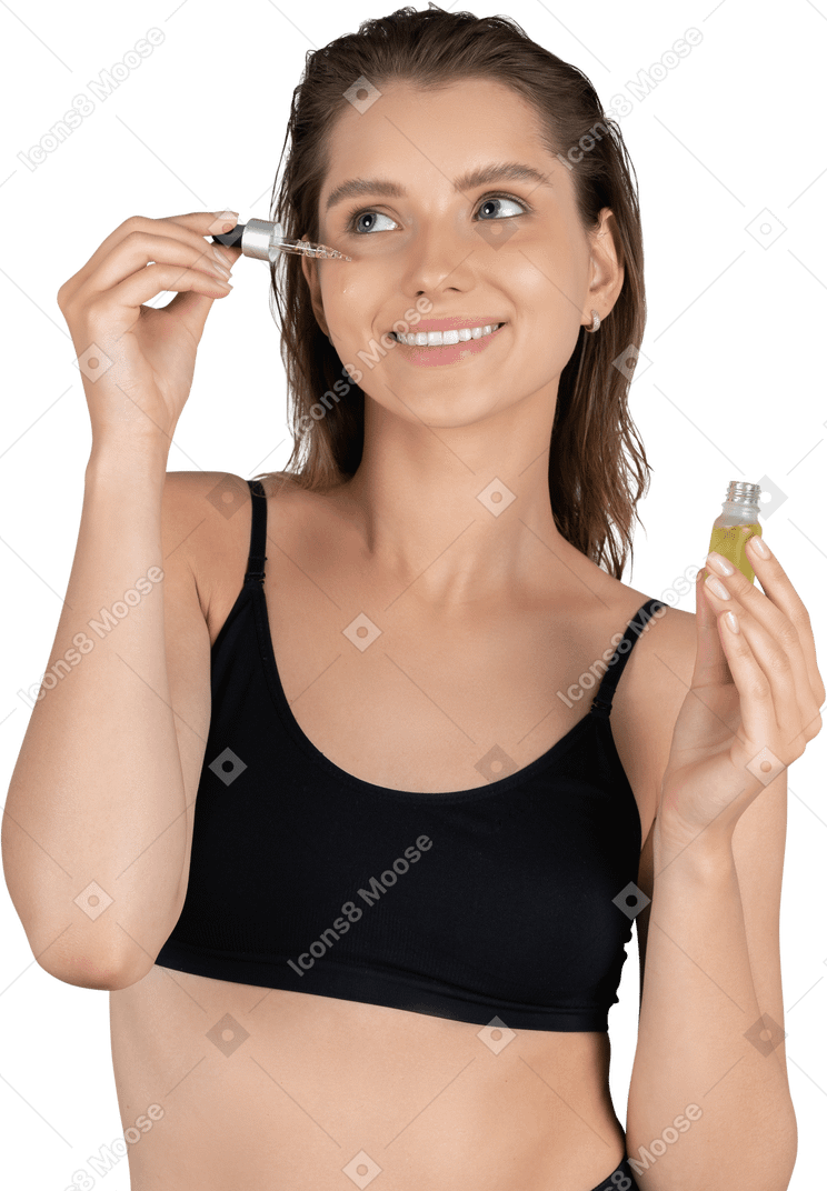 Front view of a young woman using face serum