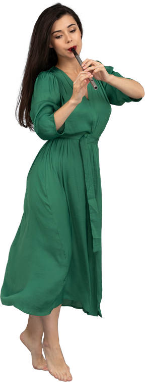플루트 연주 녹색 드레스를 입고 걷는 젊은 아가씨의 3/4보기