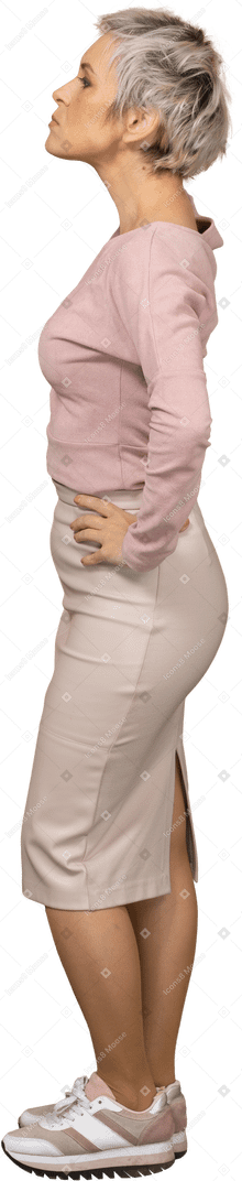 Vista lateral de uma mulher com roupas casuais, posando com as mãos na cintura
