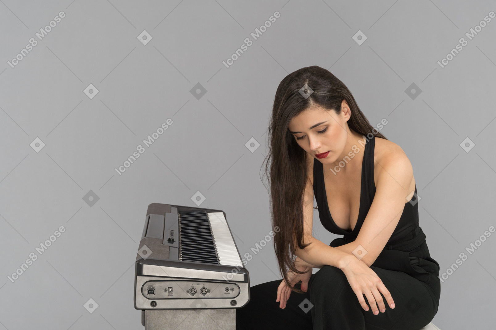 Eine nachdenkliche junge frau, die neben einem klavier sitzt