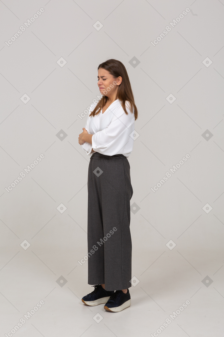 Three-quarter view of a crying young lady in office clothing crossing arms