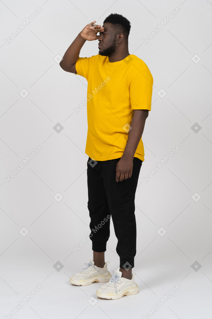 Dreiviertelansicht eines jungen dunkelhäutigen mannes in gelbem t-shirt auf der suche nach etwas