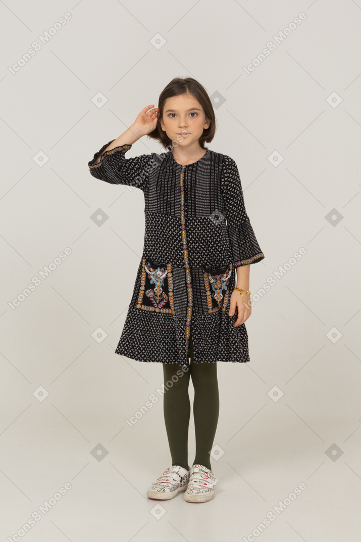 Front view of a little girl in dress fixing hair
