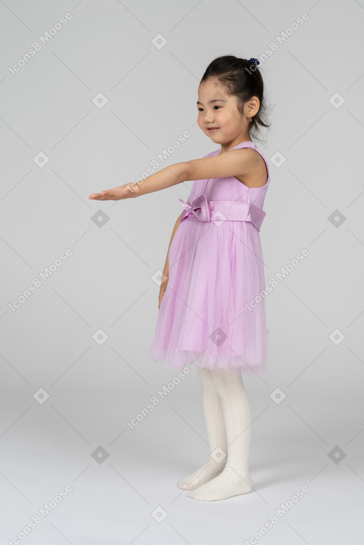 Retrato de uma menina em um vestido de tutu, estendendo o braço esquerdo