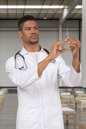 Man in a white lab coat holding a syringe