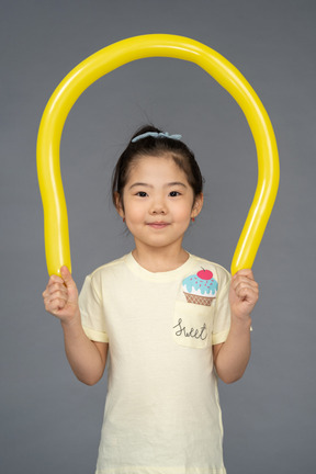 Retrato de una niña alegre sosteniendo un globo amarillo