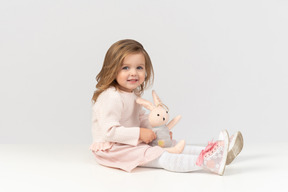 Cute little girl playing with a bunny toy