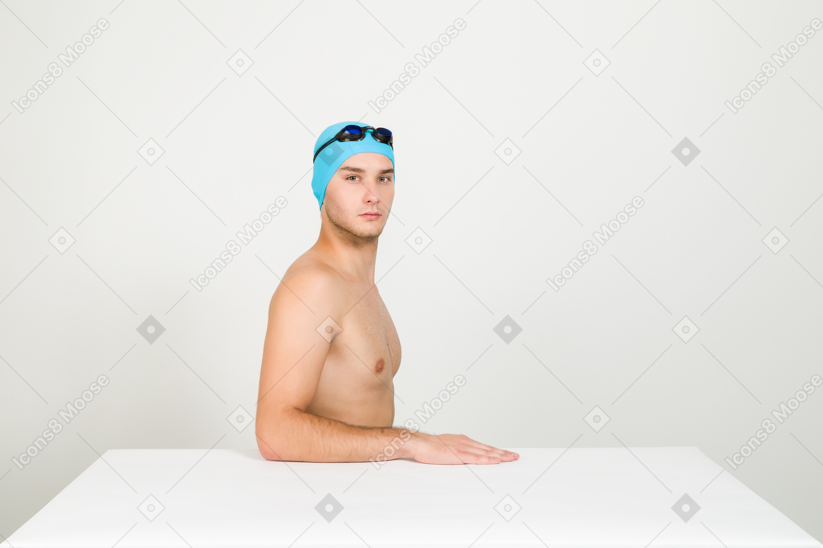 Bare chested swimmer sitting at the table in profile