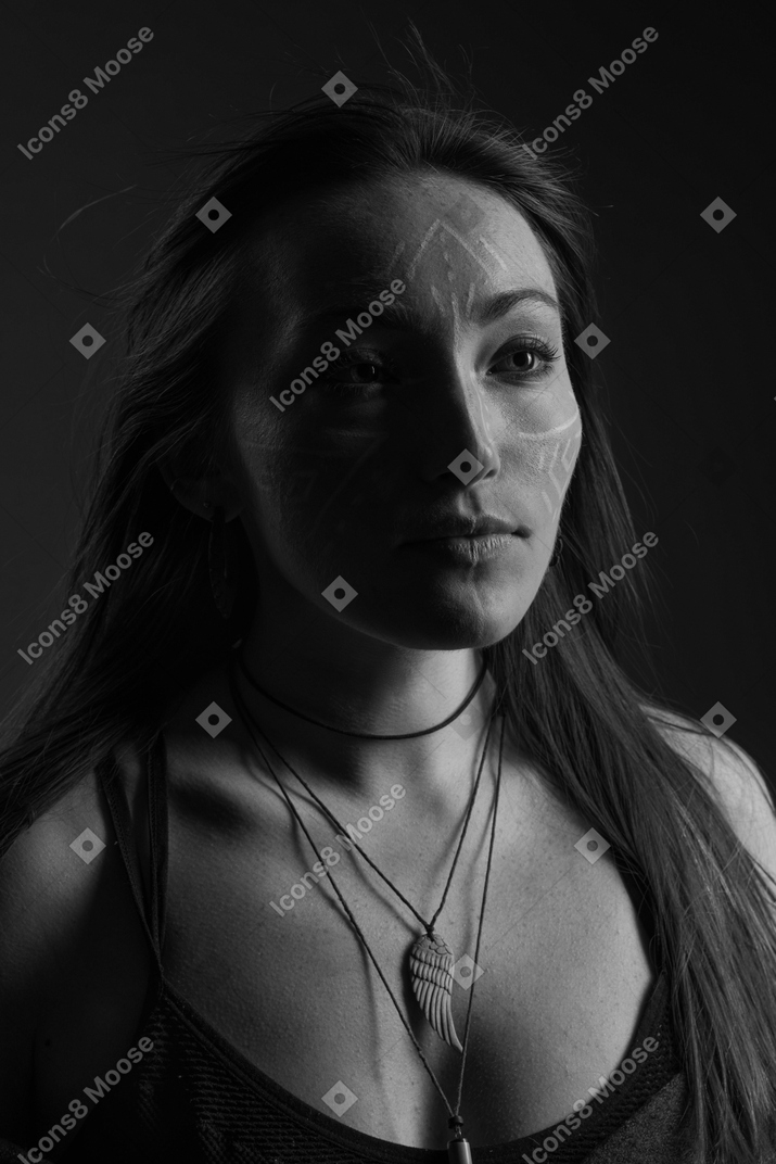 Head to shoulder noir portrait of a hopeful young female with face art looking aside