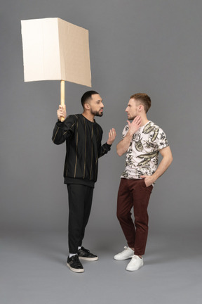 Young man with a billboard explaining something to another young man