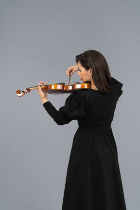 Close-up de uma jovem de vestido preto tocando violino