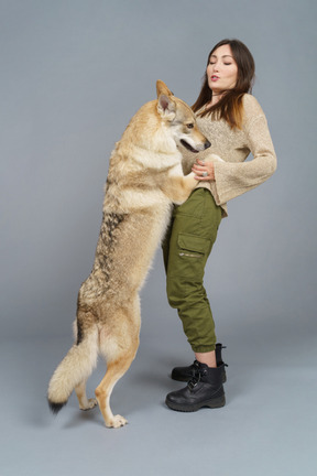 Full-length of a standing female playing with her dog