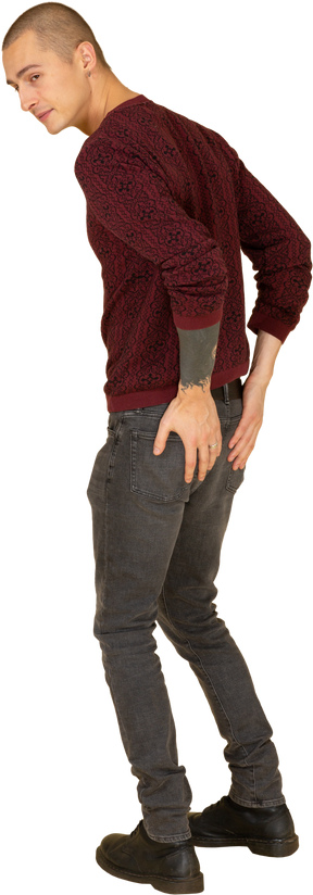 Vue de trois quarts d'un jeune homme en pull rouge touchant ses poches arrière