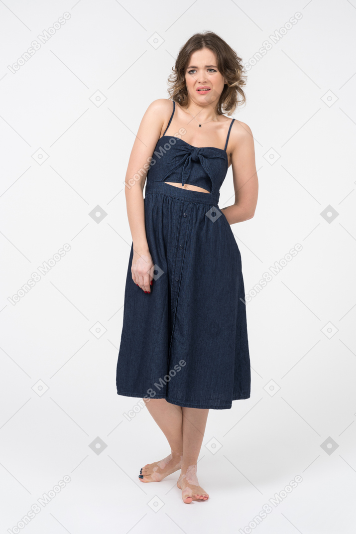 Displeased young woman keeping one hand behind while looking aside
