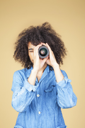 Uomo in tuta di jeans con una macchina fotografica in mano