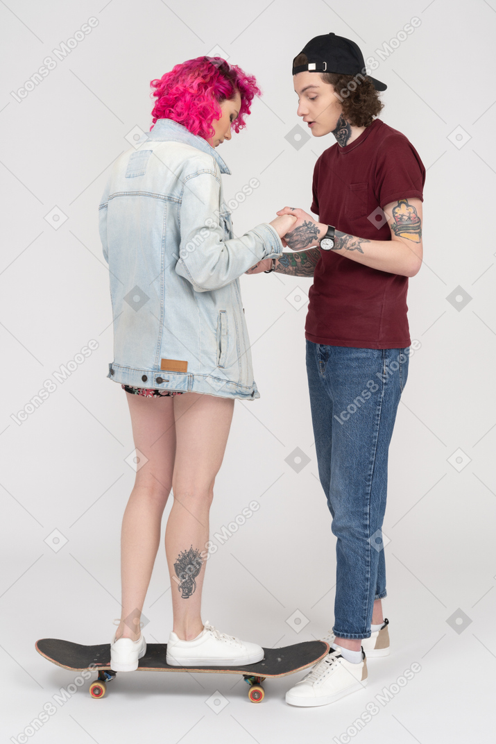 Adolescente instruyendo a su novia cómo andar en patineta