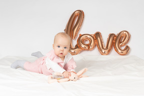 박제 장난감과 풍선 사랑 뱃속에 누워 아기 소녀는 벽에 다시 서명