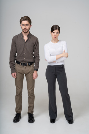 Vista frontale di una giovane coppia lunatica in abbigliamento ufficio attraversando le braccia