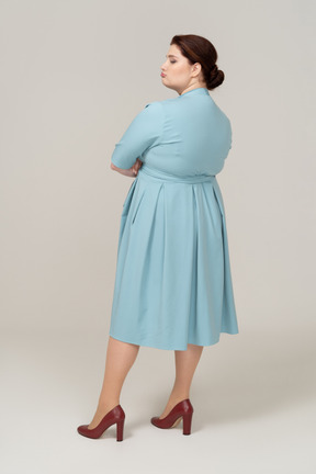 Vista posteriore di una donna in abito blu che fa smorfie