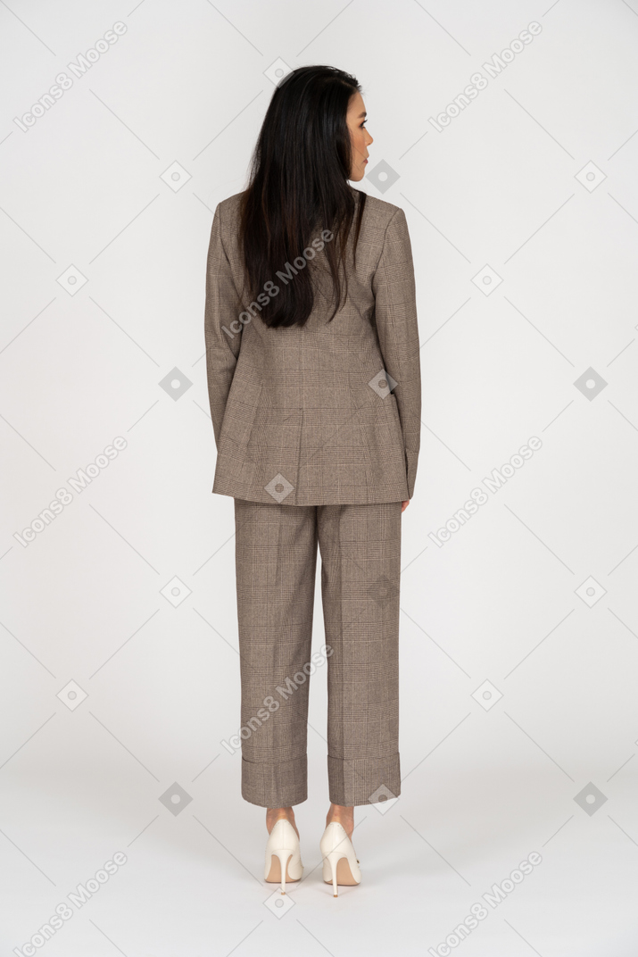 Vista posterior de una señorita en traje marrón mirando a un lado