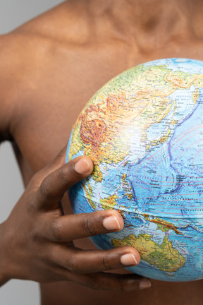 A shirtless young man holding the earth globe